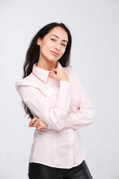 Porträt eines schönen brünetten Mädchens mit dunkler Haut in rosa Hemd, mit ernstem Gesichtsausdruck. Die emotionale Sicht der Dinge ist arrogant und hochmütig. Geschäftsfrau Portier ohne Lächeln auf weißem Hintergrund — Stockfoto