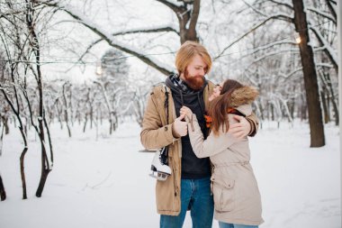 Kış ve tarih. Adama aşık genç çift ve kış karla kaplı ağaçlar Park çerçevede kadında kucaklama vardır. Uzun saç ve sakal bir adamla paten tutar ve kız seviyor