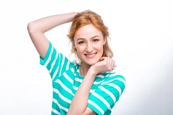 Close-up portret van een jonge, mooie vrouw met rode krullend haar in een zomerjurk met stroken van blauw in de studio op een grijze achtergrond. Thema van de zomer vakantie, toerisme en zomer kleding — Stockfoto