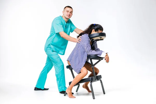 Tema masaje y oficina. Terapeuta masculino con traje azul haciendo masaje de espalda y cuello para trabajadora joven, mujer de negocios con camisa en silla de masaje shiatsu — Foto de Stock