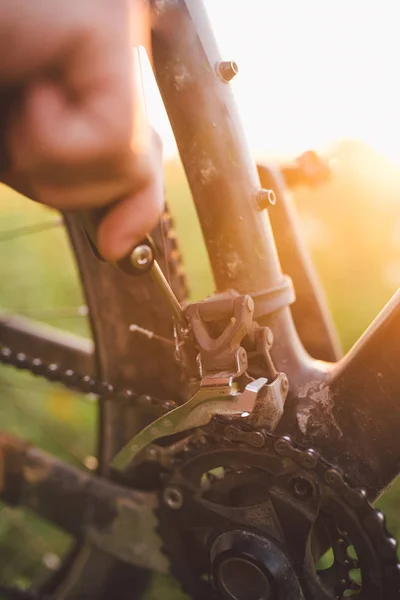 hand with a bicycle tool was engaged in fixing a bicycle outdoors at sunset