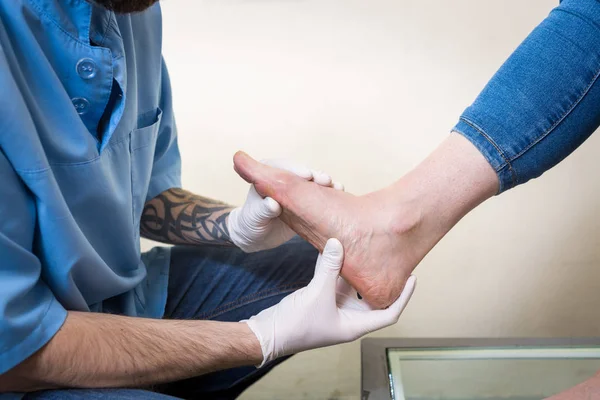 Руки молодого чоловіка лікар-ортопед проводить діагностику, тест на ногу жінки, для виготовлення індивідуальних ортопедичних устілок — стокове фото