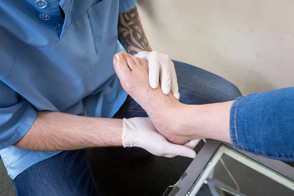 Руки молодого чоловіка лікар-ортопед проводить діагностику, тест на ногу жінки, для виготовлення індивідуальних ортопедичних устілок — стокове фото