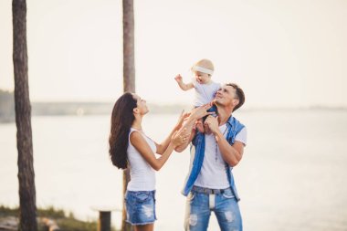 Doğada aile tatili. Üç kişi, anne, baba, kızı bir yıl denize bakan sarp kayalığın üzerinde harcamak. Genç oyun, etrafında insanlar ve gülmek. Şık denim giysileri giymiş şık güzel insanlar