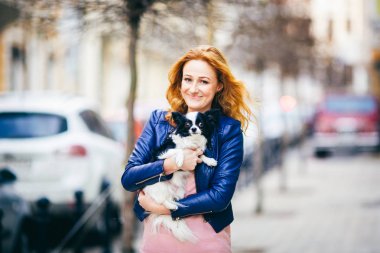 Konu adam ve bir köpek. Genç Kızıl saçlı beyaz bir kadın yüzündeki çiller ile siyah beyaz tüylü chihuahua cins köpek tutar. Mavi deri ceket giymiş kız bahar aylarında işlek cadde üzerinde duruyor