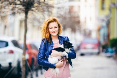Konu adam ve bir köpek. Genç Kızıl saçlı beyaz bir kadın yüzündeki çiller ile siyah beyaz tüylü chihuahua cins köpek tutar. Mavi deri ceket giymiş kız bahar aylarında işlek cadde üzerinde duruyor