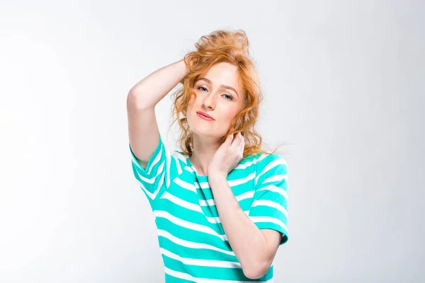 Retrato de cerca de una joven y hermosa mujer con el pelo rizado rojo en un vestido de verano con tiras de azul en el estudio sobre un fondo gris. Tema de vacaciones de verano, turismo y ropa de verano —  Fotos de Stock