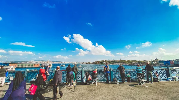 27 de octubre de 2019 Estambul. Pavo. Pescador pescando en el puente de Galata en Estambul Turquía. La gente camina por el puente de Galata. Vacaciones en Estambul. Puente de Galata lugar tradicional favorito para la pesca — Foto de Stock