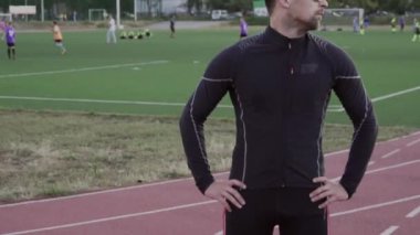 Tema spor ve sağlık. Kafkas erkek portresi spor giyim güneş gözlüğü. Spor dersi şehir stadyumu koşu bandı. Koşucu dışarıda koşuyor, boynun kaslarını ısıtıyor.