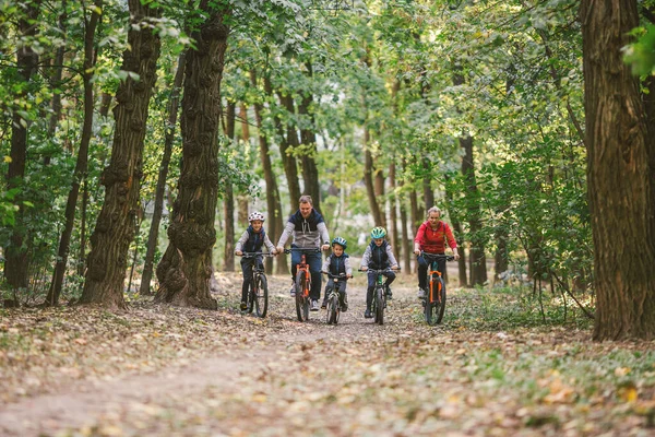 Rodziców i dzieci jeżdżących po leśnym szlaku. Młoda rodzina jeździ na rowerze w jesiennym parku. Rodzinny rower górski po lesie. Rodziny tematyczne aktywny sport rekreacji na świeżym powietrzu. Jazda na rowerze rodzinnym przez jesienny las — Zdjęcie stockowe