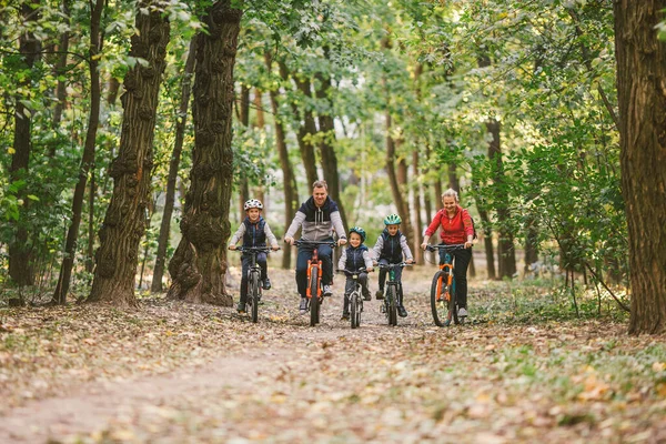 Rodziców i dzieci jeżdżących po leśnym szlaku. Młoda rodzina jeździ na rowerze w jesiennym parku. Rodzinny rower górski po lesie. Rodziny tematyczne aktywny sport rekreacji na świeżym powietrzu. Jazda na rowerze rodzinnym przez jesienny las — Zdjęcie stockowe