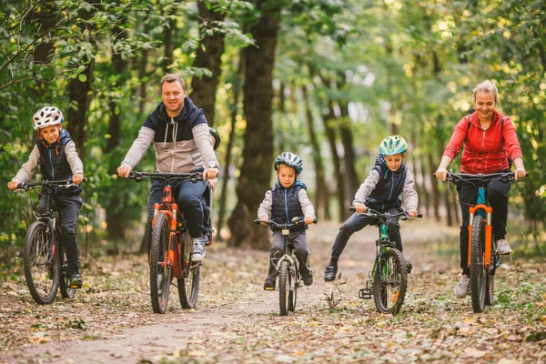 Parents and kids cycling on forest trail. Young family in warm clothes cycling in autumn park. Family mountain biking on forest. Theme family active sports outdoor recreation. — Stock Photo, Image