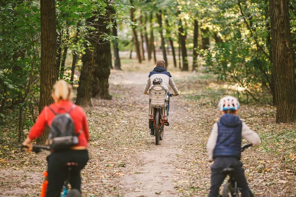 Rodziców i dzieci jeżdżących po leśnym szlaku. Młoda rodzina jeździ na rowerze w jesiennym parku. Rodzinny rower górski po lesie. Rodziny tematyczne aktywny sport rekreacji na świeżym powietrzu. Jazda na rowerze rodzinnym przez jesienny las — Zdjęcie stockowe