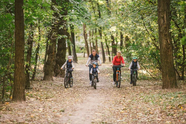 Rodziców i dzieci jeżdżących po leśnym szlaku. Młoda rodzina jeździ na rowerze w jesiennym parku. Rodzinny rower górski po lesie. Rodziny tematyczne aktywny sport rekreacji na świeżym powietrzu. Jazda na rowerze rodzinnym przez jesienny las — Zdjęcie stockowe