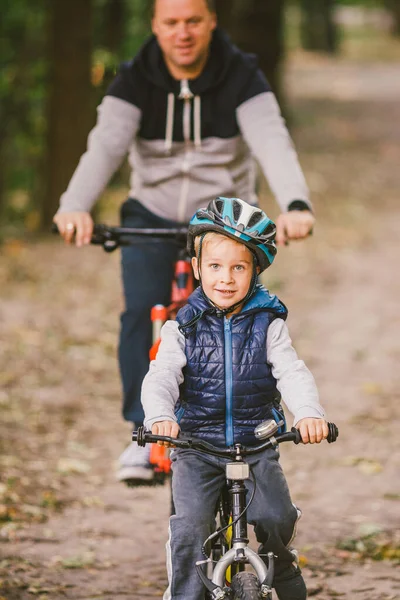 Родители и дети катаются на велосипеде по лесной тропе. семья в теплой одежде велосипедного осеннего парка. Семейный горный велосипед в лесу. активный спортивный отдых на открытом воздухе. Портрет семьи, путешествующей по осеннему лесу — стоковое фото