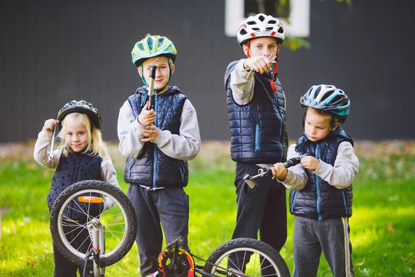 Mechanika dziecięca, naprawa rowerów. Szczęśliwe dzieci naprawiają rower razem na świeżym powietrzu w słoneczny dzień. Koncepcja naprawy rowerów. Rodzina pracy zespołowej pozowanie z narzędziami do naprawy roweru w rękach na zewnątrz — Zdjęcie stockowe