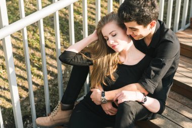 Güzel, genç, çok kültürlü bir çift, birbirine aşık öğrenci bir çift, şehirde ahşap merdivenlerde oturuyor. Güzel Türk esmer adam siyah elbiseli beyaz bir kıza sarılıyor. Güneşli havalarda genç insanlarla çık