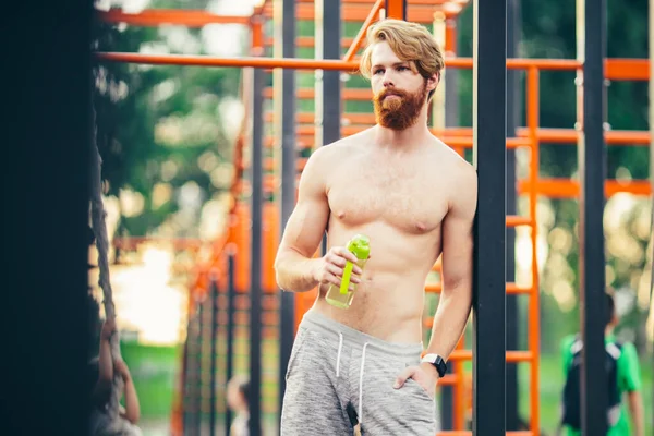 Soif et santé. Un sportif tient une bouteille d'eau sur le stade. Convient à l'homme avec une fiole en plastique extérieure. Restez hydraté et en bonne santé. Sport et fitness — Photo