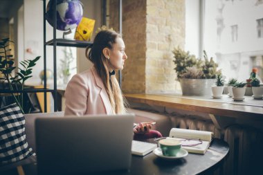 Kahve masasında oturan, kahve içen ve akıllı telefon kullanan bir kadın. Kafede Telefon Kullanan Kadın. Öğrenci çevrimiçi öğreniyor. Kız mailleri kontrol ediyor. Kadın Kafe, cep telefonu kullan, çalışan defter