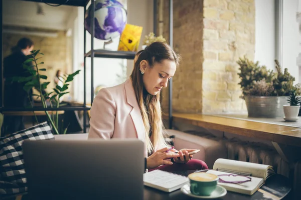 Mujer sentada cafetería mesa de madera, beber café y el uso de teléfono inteligente. Mujer usando el teléfono en el café. Aprendizaje de estudiantes online. Chica revisando correo electrónico. Mujer Café, uso de teléfono móvil, Cuaderno de trabajo — Foto de Stock