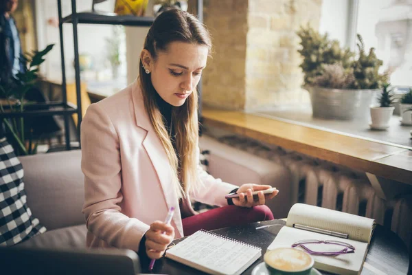 Mujer sentada cafetería mesa de madera, beber café y el uso de teléfono inteligente. Mujer usando el teléfono en el café. Aprendizaje de estudiantes online. Chica revisando correo electrónico. Mujer Café, uso de teléfono móvil, Cuaderno de trabajo — Foto de Stock