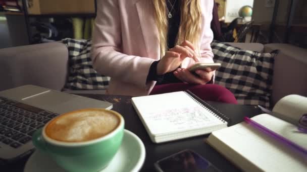 Donna seduta caffetteria tavolo in legno, bere caffè e utilizzando smartphone. Donna che usa il telefono nel caffè. Studente che impara online. Ragazza controlla e-mail. Donna Cafe, utilizzare il telefono cellulare, notebook di lavoro — Video Stock