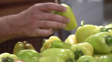 Denek süpermarketten sebze alıyor. Kafkasyalı genç bir adamın eli, yeşil bir bogarsky biberi seçer ve malları değerlendirir ve sepete koyar.