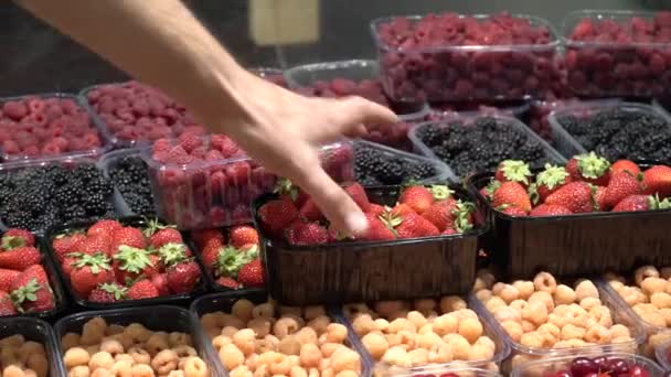 白人男性の手は新鮮な熟した完璧な果物の箱からイチゴを取ります。食物の背景、トップビュー、自然光 — ストック動画