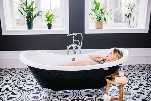 Interior de moderno baño minimalista de lujo con ventana. Tema moda y estilo. Mujeres ricas en vacaciones en el hotel spa caro. Modelo de retrato de moda en el baño — Foto de Stock