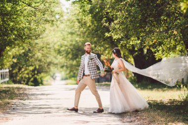 Güzel bir düğün çifti ormanı. Gelin ve damat, beni takip edin, evli çift, beyaz gelinlik ve duvak giyen kadın. Kırsal kesim aşk hikayesi. Hipster fotoğrafımı takip et. Yeni evliler el ele yürüyorlar.
