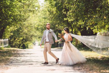 Güzel bir düğün çifti ormanı. Gelin ve damat, beni takip edin, evli çift, beyaz gelinlik ve duvak giyen kadın. Kırsal kesim aşk hikayesi. Hipster fotoğrafımı takip et. Yeni evliler el ele yürüyorlar.