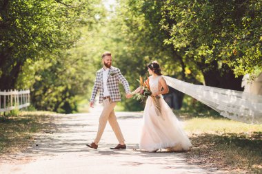 Güzel bir düğün çifti ormanı. Gelin ve damat, beni takip edin, evli çift, beyaz gelinlik ve duvak giyen kadın. Kırsal kesim aşk hikayesi. Hipster fotoğrafımı takip et. Yeni evliler el ele yürüyorlar.