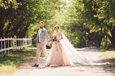 Güzel bir düğün çifti ormanı. Gelin ve damat, beni takip edin, evli çift, beyaz gelinlik ve duvak giyen kadın. Kırsal kesim aşk hikayesi. Hipster fotoğrafımı takip et. Yeni evliler el ele yürüyorlar.