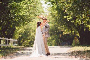 Damat mutlu gelini kucaklıyor. Gün batımı güneşli hava. Mutlu yeni evliler bahçede yan yana duruyor. temalı bir düğün portresi ve güzel bir gelinlik. Düğün çifti dışarıda sarılıp öpüşüyor.