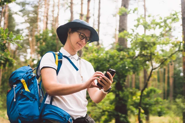 Menina turista uso smartphone na caminhada, olha mapas e navegação. Mulher com mochila usando telefone inteligente na bela natureza.Conceito de viagem. Viagem ao ar livre. Viaje e explore. Turista feminina usando gps — Fotografia de Stock