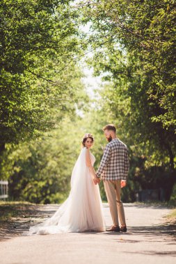 Damat mutlu gelini kucaklıyor. Gün batımı güneşli hava. Mutlu yeni evliler bahçede yan yana duruyor. temalı bir düğün portresi ve güzel bir gelinlik. Düğün çifti dışarıda sarılıp öpüşüyor.
