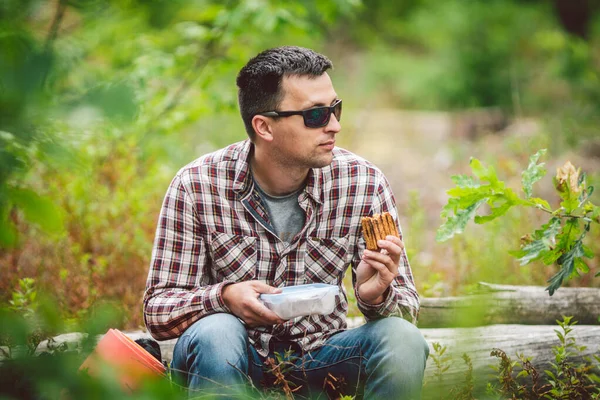 Hungry man eating. Sandwich outdoors. hiker eating sandwich sitting in forest. tourist eat snack food. Hiker take break with time for food. Caucasian guy tourist bring splastic box with sandwich — Stock Photo, Image