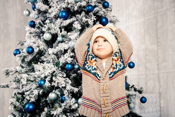 Christmas theme and children. Little Caucasian boy child in a warm hat and sweater posing, eating sweetness, dirty face. Christmas morning. New Years holidays — Stock Photo, Image