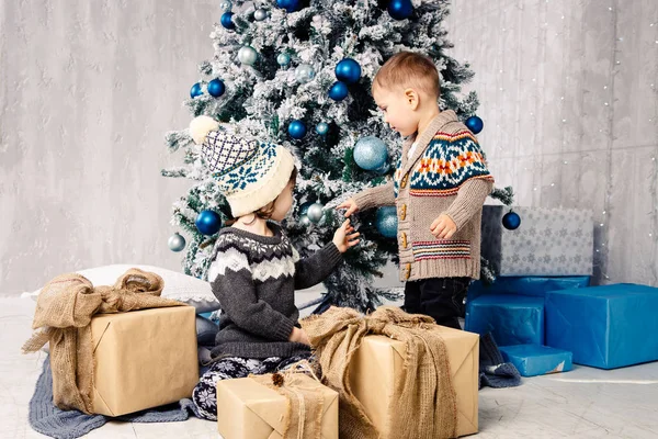 Hermano y hermana con cajas de regalo. Sentada bajo el árbol de Navidad. hermano y hermana se divierten abriendo regalos bajo el árbol de Navidad. Niños con regalos de Navidad — Foto de Stock