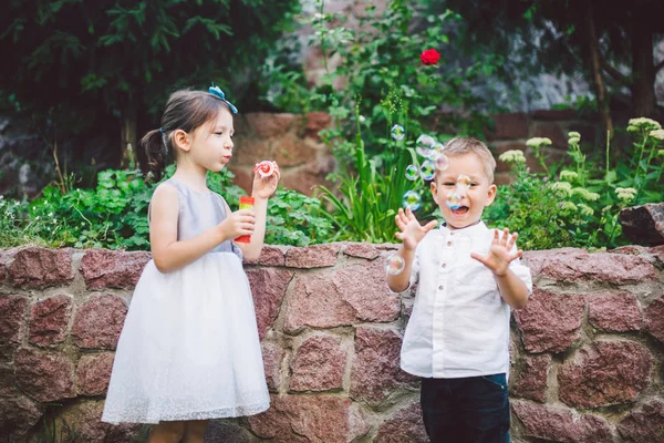 Zwei Kinder im Park pusten Seifenblasen und haben Spaß. Zwei Babys spielen mit Seifenblasen. Bruder und Schwester Spaß an der frischen Luft, glückliche Kindheit — Stockfoto