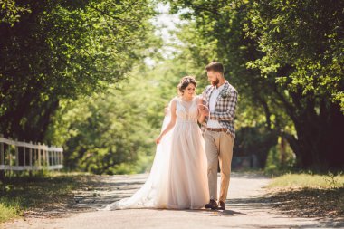 Düğün çifti ormanda yürümeyi sever. Yeni evliler kucaklaşır ve el ele tutuşur. Yeni evliler güneşli bir havada parkta el ele yürür. Düğün ve nişan teması