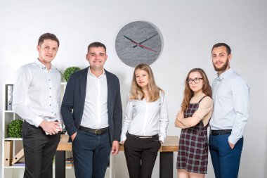 Gülümseyen çalışanlar kameraya bakıp ofiste takım fotoğrafı çekiyorlar. İş Adamları Takımı. Mutlu işçilerle başarılı bir birliktelik. İletişim Kurumsal Takım Çalışması Konseptiyle Tanışan İnsanlar