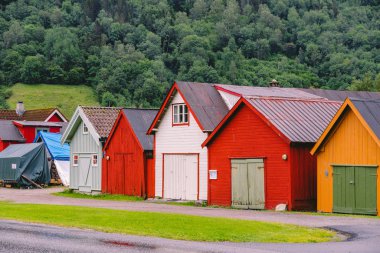 Renkli ahşap binaların kırsal manzarası. Norveç 'teki kayıkhaneler. İskandinav geleneksel kayıkhaneleri. Norveç 'in kıyı kesimindeki çok renkli garaj ahşap evleri