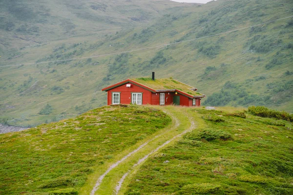 Hütte hölzerne Berghütten in Passnorwegen. norwegische Landschaft mit typisch skandinavischen Grasdachhäusern. Bergdorf mit kleinen Häusern und Holzhütten mit Gras auf dem Dach im Tal — Stockfoto