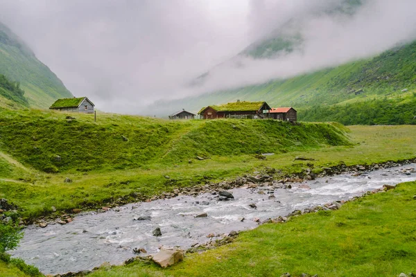 Chata dřevěné horské chaty v horském průsmyku Norsko. Norská krajina s typickými skandinávskými střešními domy. Horská vesnice s malými domky a dřevěnými chatkami s trávou na střeše v údolí — Stock fotografie