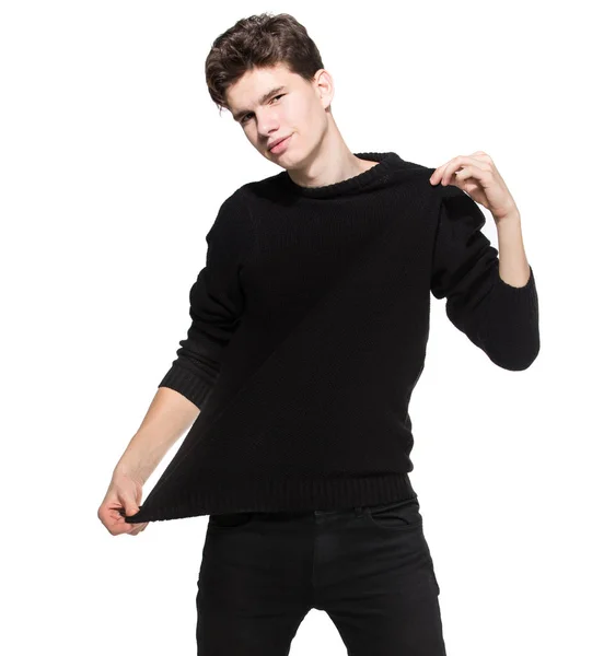 Mladý muž model v černém oblečení pózuje ve studiu bílé pozadí. Běloch ve stylovém svetru a džínách je izolovaný. Módní model mladý bílý muž — Stock fotografie