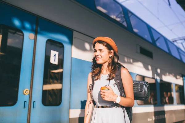 Turismo e viagens no verão. Férias para o estudante. Trabalho e viagens. Mulher branca bebe café na plataforma da estação ferroviária no fundo do trem — Fotografia de Stock