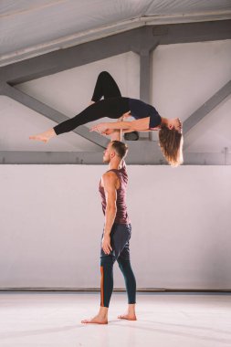 Tema Acroyoga ve Yoga teşkil etmektedir. Bir çift iki erkek ve bir kadın asana pozisyonda durmak. Adam kız yüksek sırt üstü uzanmış kolu kemerli tutar. Spor salonunda bir stüdyo arka ışık ile
