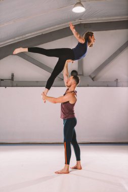 Tema Acroyoga ve Yoga teşkil etmektedir. Bir çift iki erkek ve bir kadın asana pozisyonda durmak. Adam kız yüksek sırt üstü uzanmış kolu kemerli tutar. Spor salonunda bir stüdyo arka ışık ile