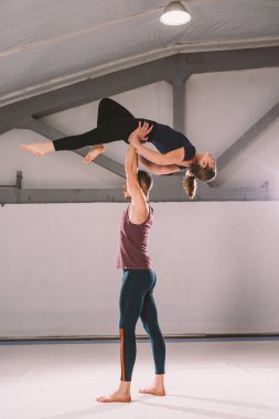Tema Acroyoga ve Yoga teşkil etmektedir. Bir çift iki erkek ve bir kadın asana pozisyonda durmak. Adam kız yüksek sırt üstü uzanmış kolu kemerli tutar. Spor salonunda bir stüdyo arka ışık ile